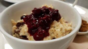 Una ciotola di porridge con composta di frutta rossa su un piatto bianco.