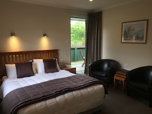 A hotel room with a large bed, two bedside tables, a chair, and a painting on the wall.