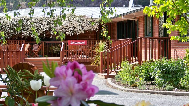 Un restaurant doté d’une terrasse en bois, de places assises en plein air et d’une enseigne indiquant son nom.