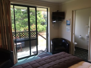 A hotel room with a bed, a chair, a TV, and a bathroom.