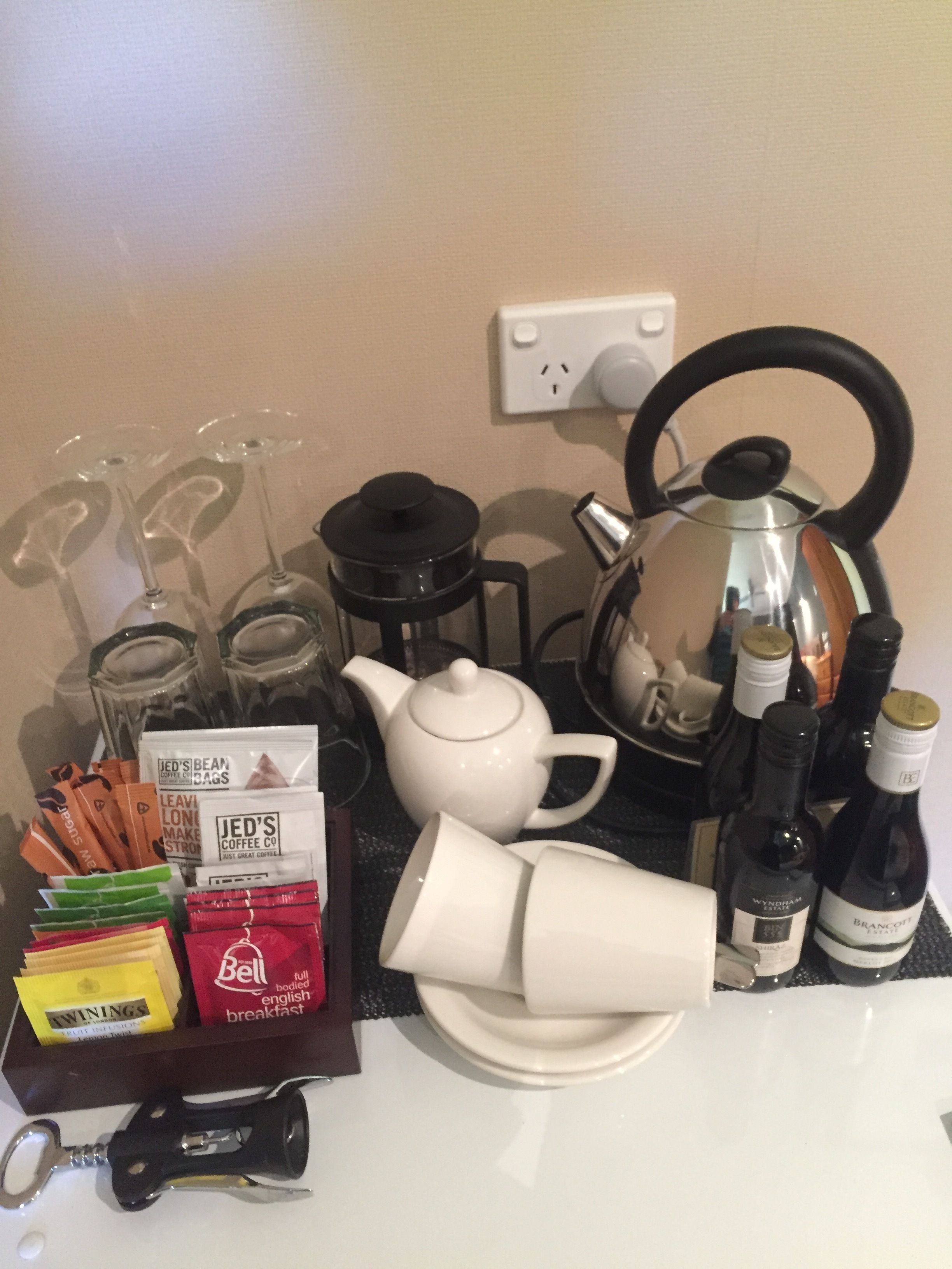 A tea set including a teapot, cups, and a sugar bowl, along with various coffee pods and a bottle of wine.