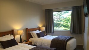 Une chambre d’hôtel avec deux lits, une fenêtre avec des rideaux, une lampe et un téléviseur.