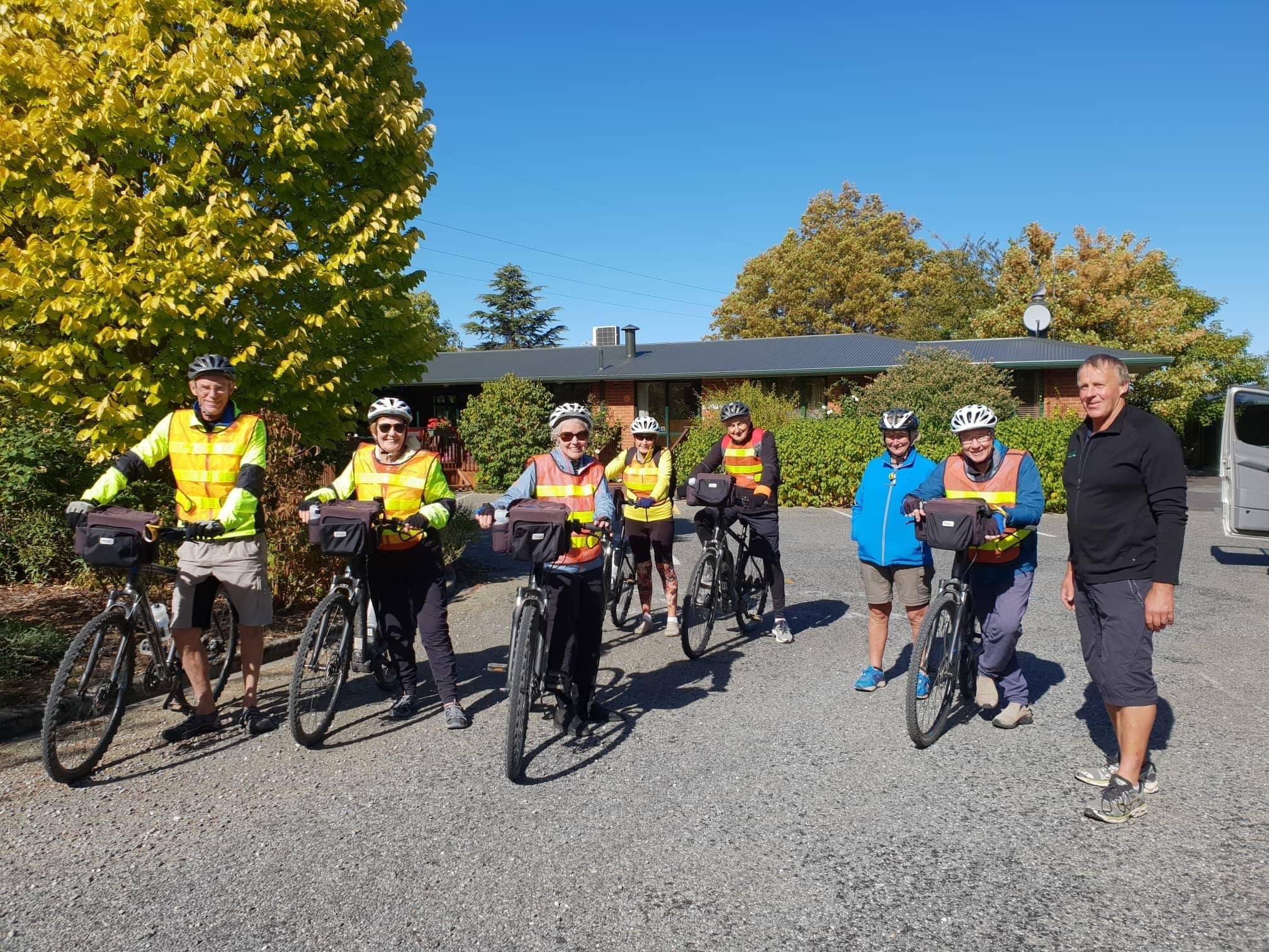 A group of cyclists in reflective vests standing in a parking lot.