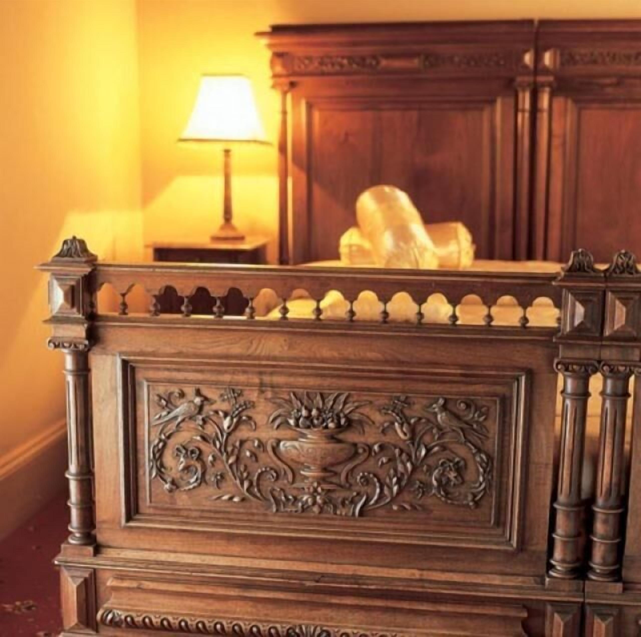 A wooden bed frame with intricate carvings and a decorative headboard.