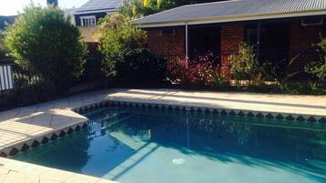 Relax by the rectangular pool surrounded by a tiled deck and lush greenery.