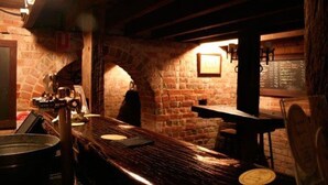 Een rustieke bar met zichtbare bakstenen muren, houten balken en een bakoven.