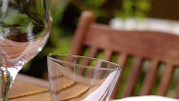 A wooden table with two clear glasses and a folded napkin with cutlery.
