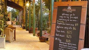 Een restaurant met een schoolbord waarop gerechten staan vermeld, zoals pompoensoep en gegrilde bruschetta.