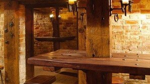 Een rustieke bar met een lange houten tafel en drie krukken.