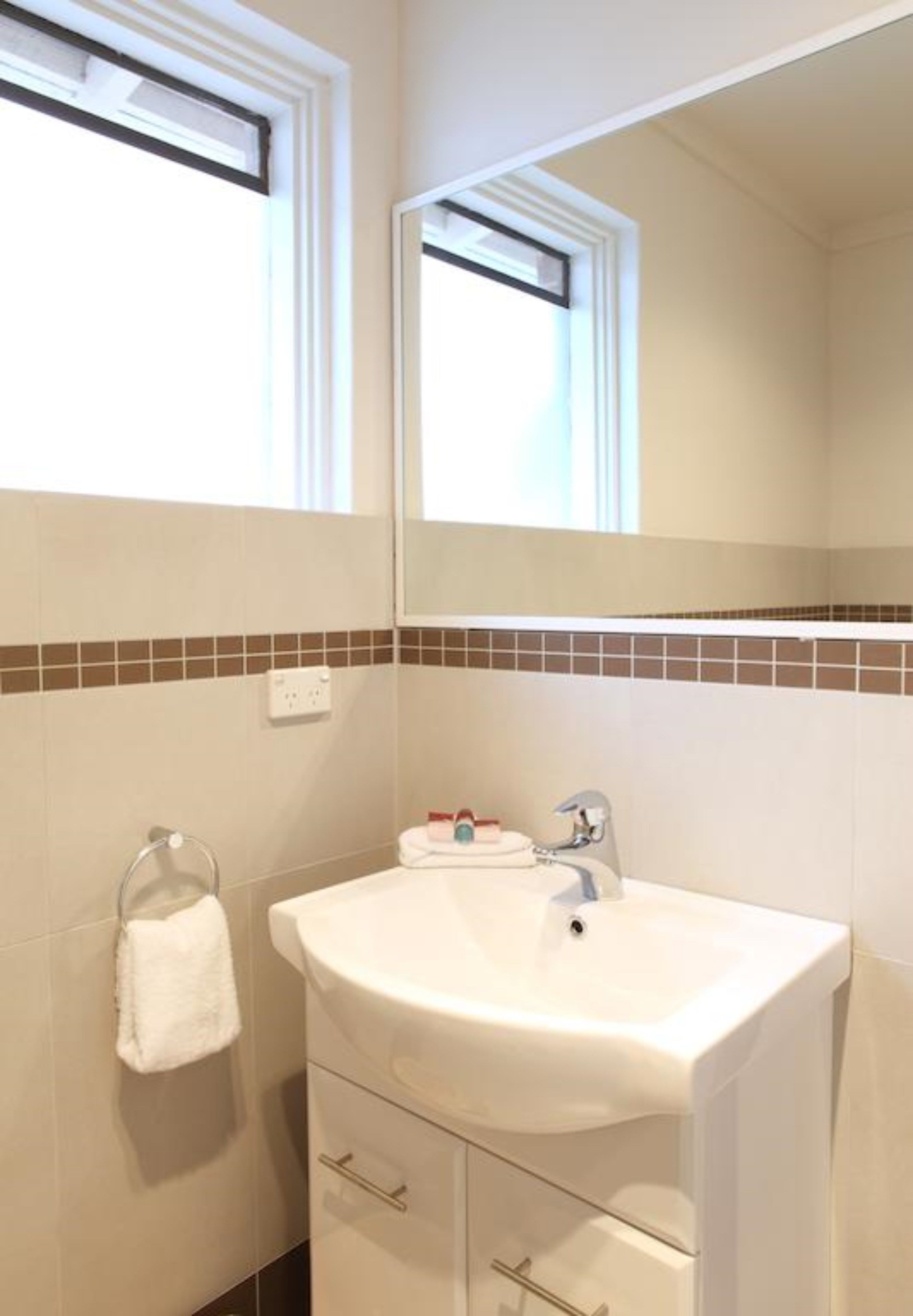 A bathroom with a white sink, a towel rack, and a mirror.