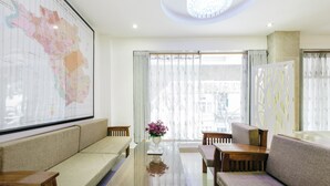 Un hotel moderno con un mapa grande en la pared, un sofá, una mesa y vistas a la ciudad desde la ventana.