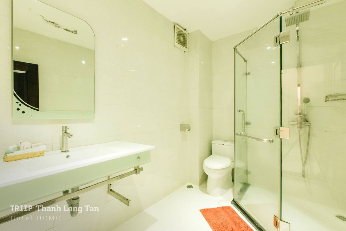 A modern bathroom with a glass-enclosed shower, a white sink, and a toilet.