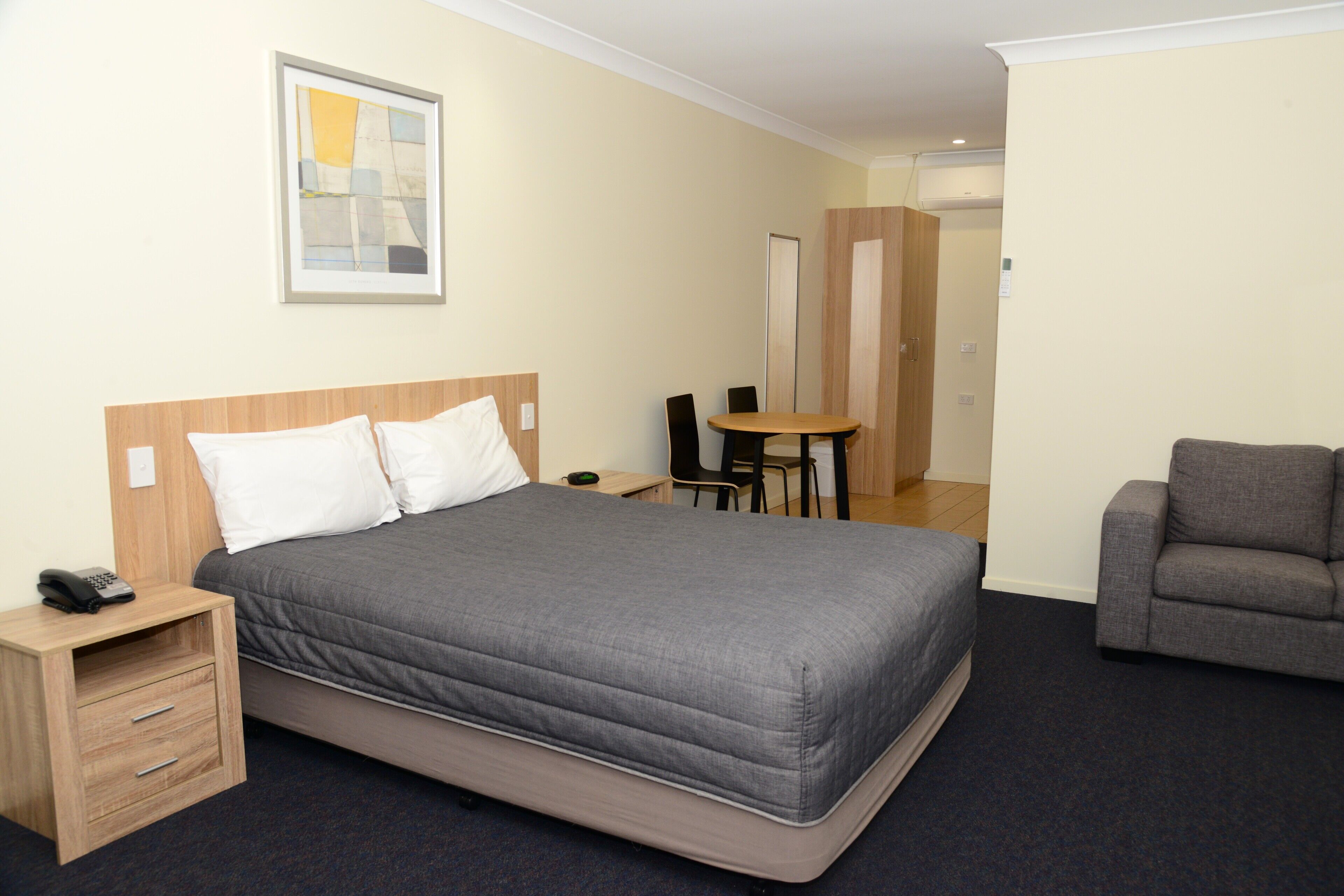 Ein Hotelzimmer mit einem Bett, einem Nachttisch, einem Sessel und einem kleinen Tisch mit Stuhl.