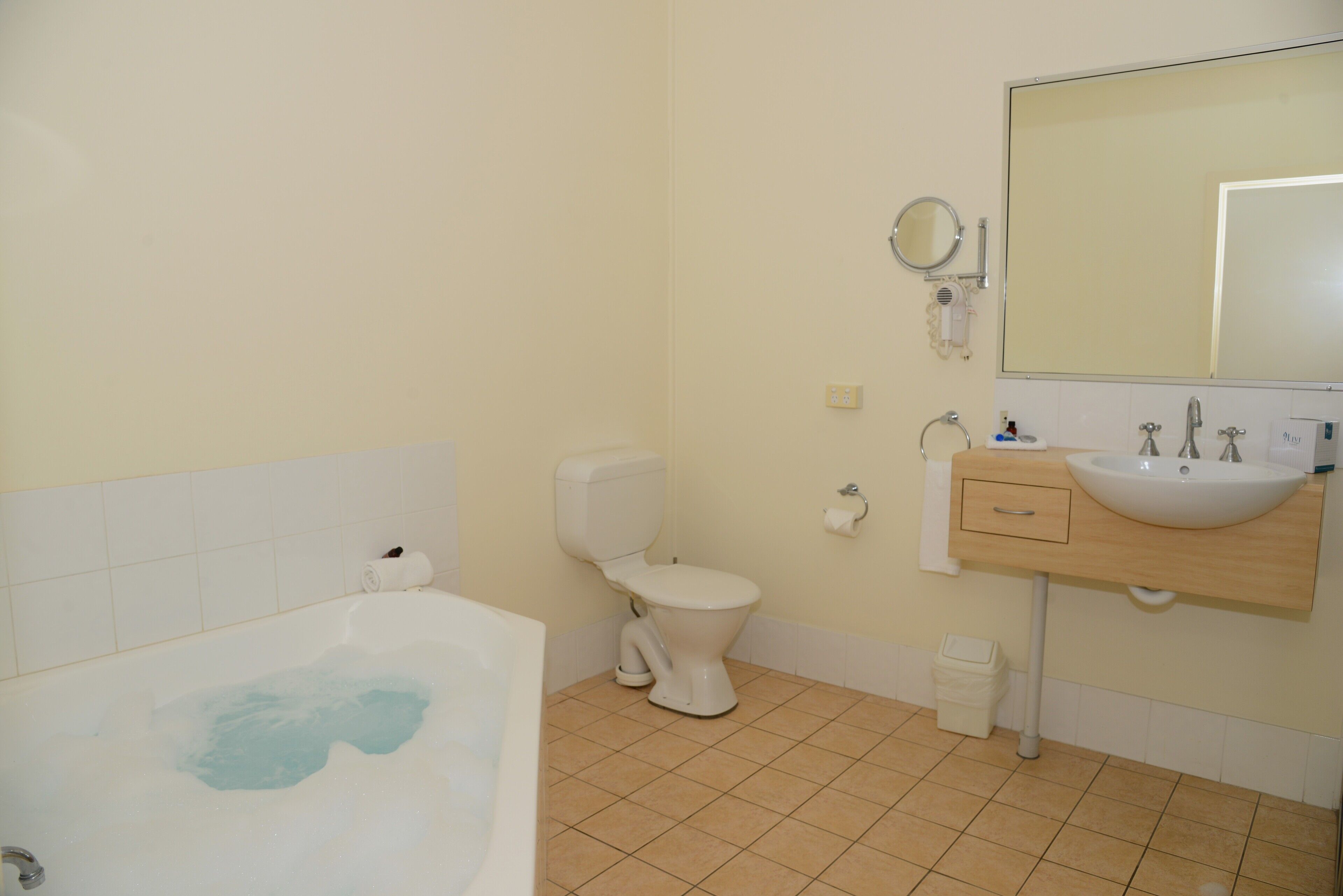 A bathroom with a bathtub, toilet, sink, and mirror.