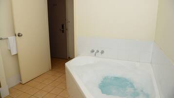 Un bagno con una vasca, un porta asciugamani e una porta che dà su un'altra stanza.