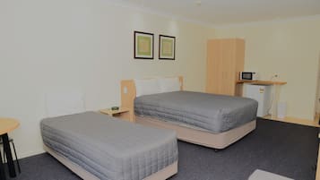 Una habitación de hotel con dos camas, un escritorio pequeño, un microondas y un armario.