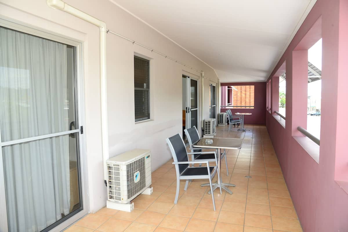 Corredor com área de jantar, mesa, cadeiras, aparelhos de ar condicionado e vista para a rua.