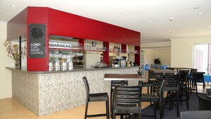 En lobbycafébar og lounge med en rød bardisk, barstole og et ur på væggen.