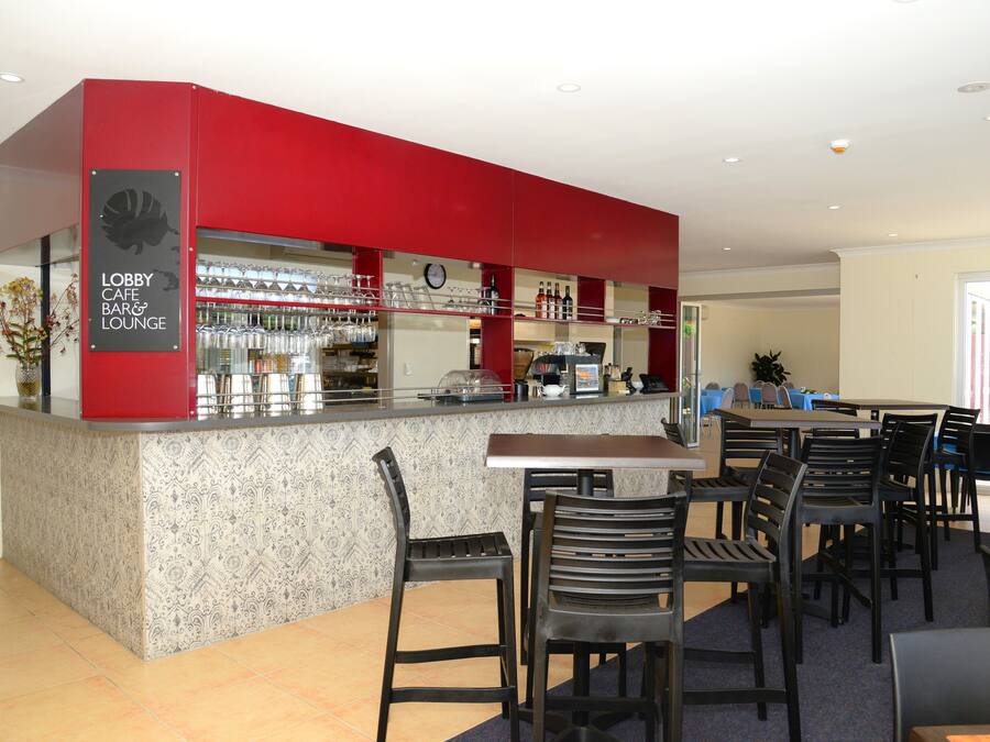 A lobby cafe bar & lounge with a red counter, bar stools, and a clock on the wall.