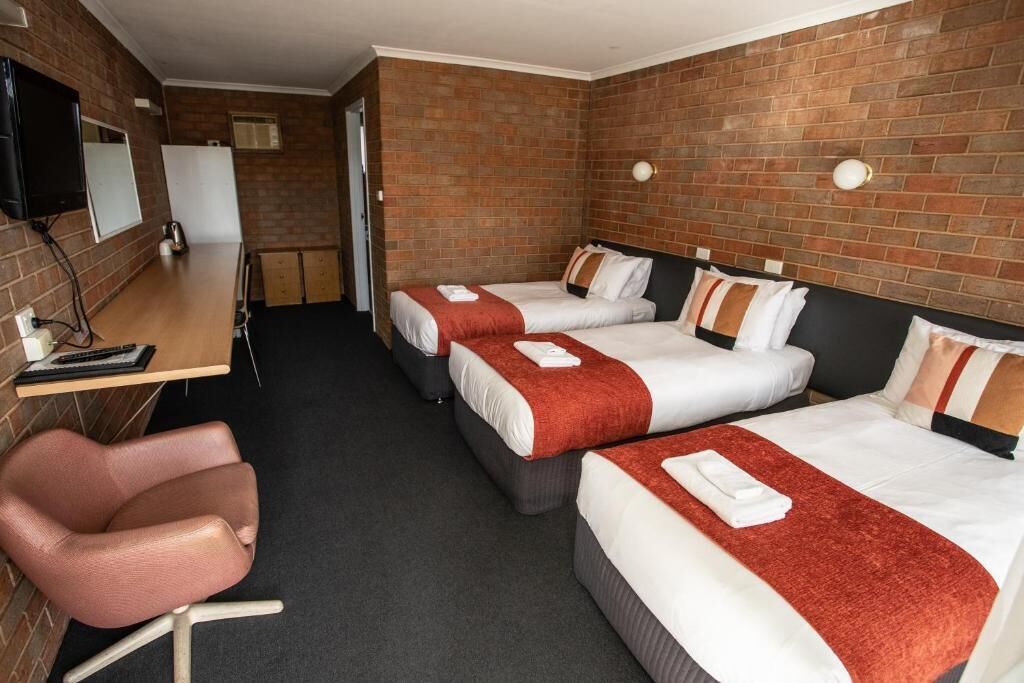 Une chambre d’hôtel avec deux lits, un bureau, une chaise et un téléviseur.