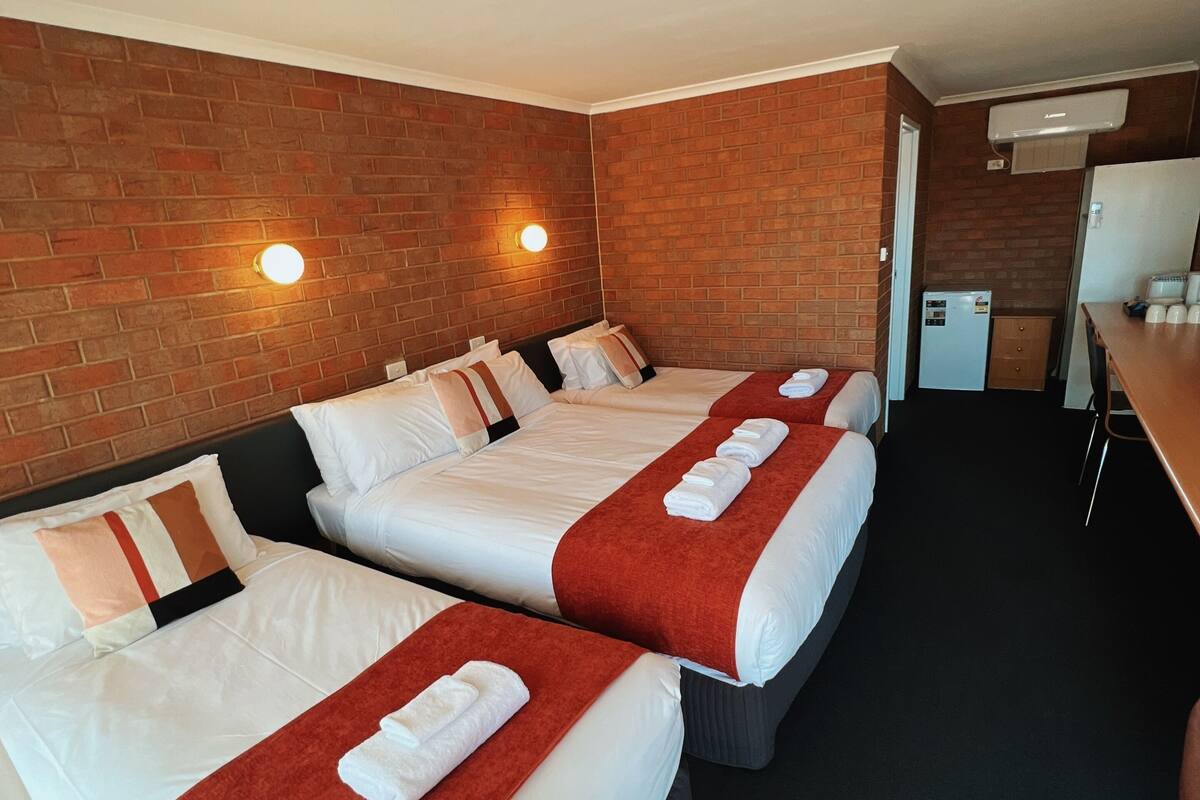 Une chambre d’hôtel avec deux lits, une petite kitchenette et un mur en briques.