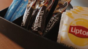En kaffemaskine og en bakke med kaffekapsler og en Lipton tepose.