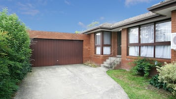 A residential house with a brown garage door, a front entrance with a small porch, and a clear sky.
