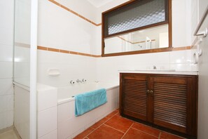 A bathroom with a bathtub, a sink, and a mirror.