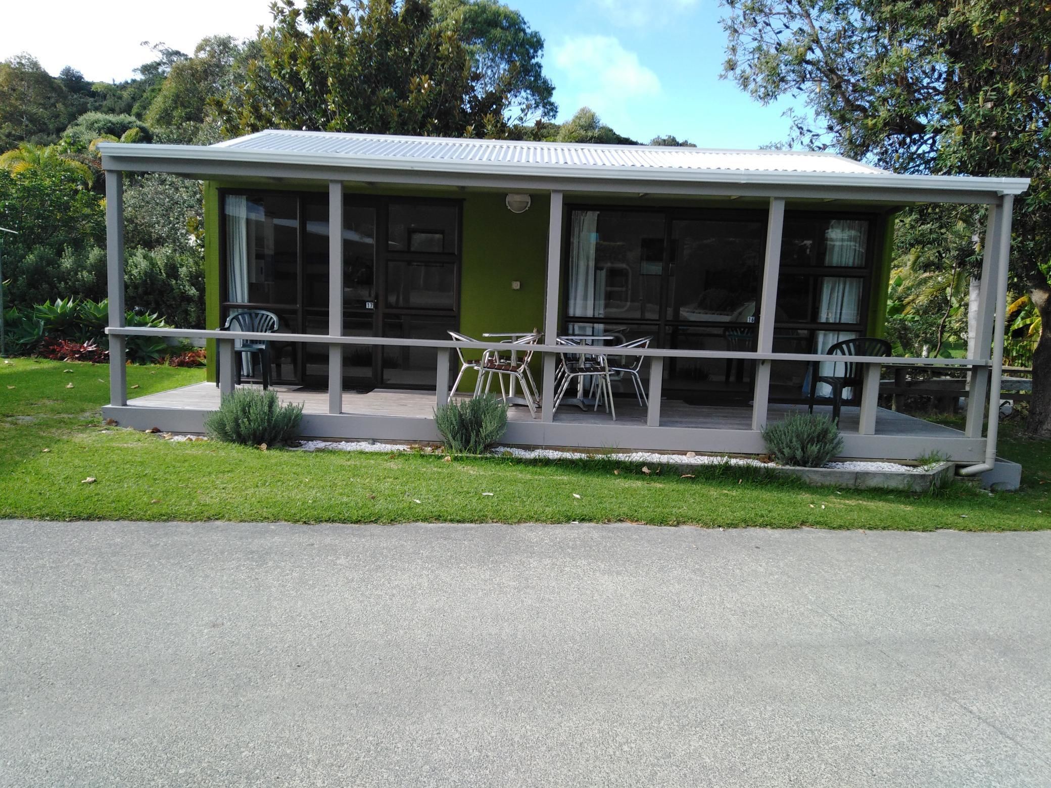 Una casa moderna con patio coperto, ampie finestre e una porta verde.