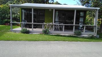 Una casa moderna con patio coperto, ampie finestre e una porta verde.