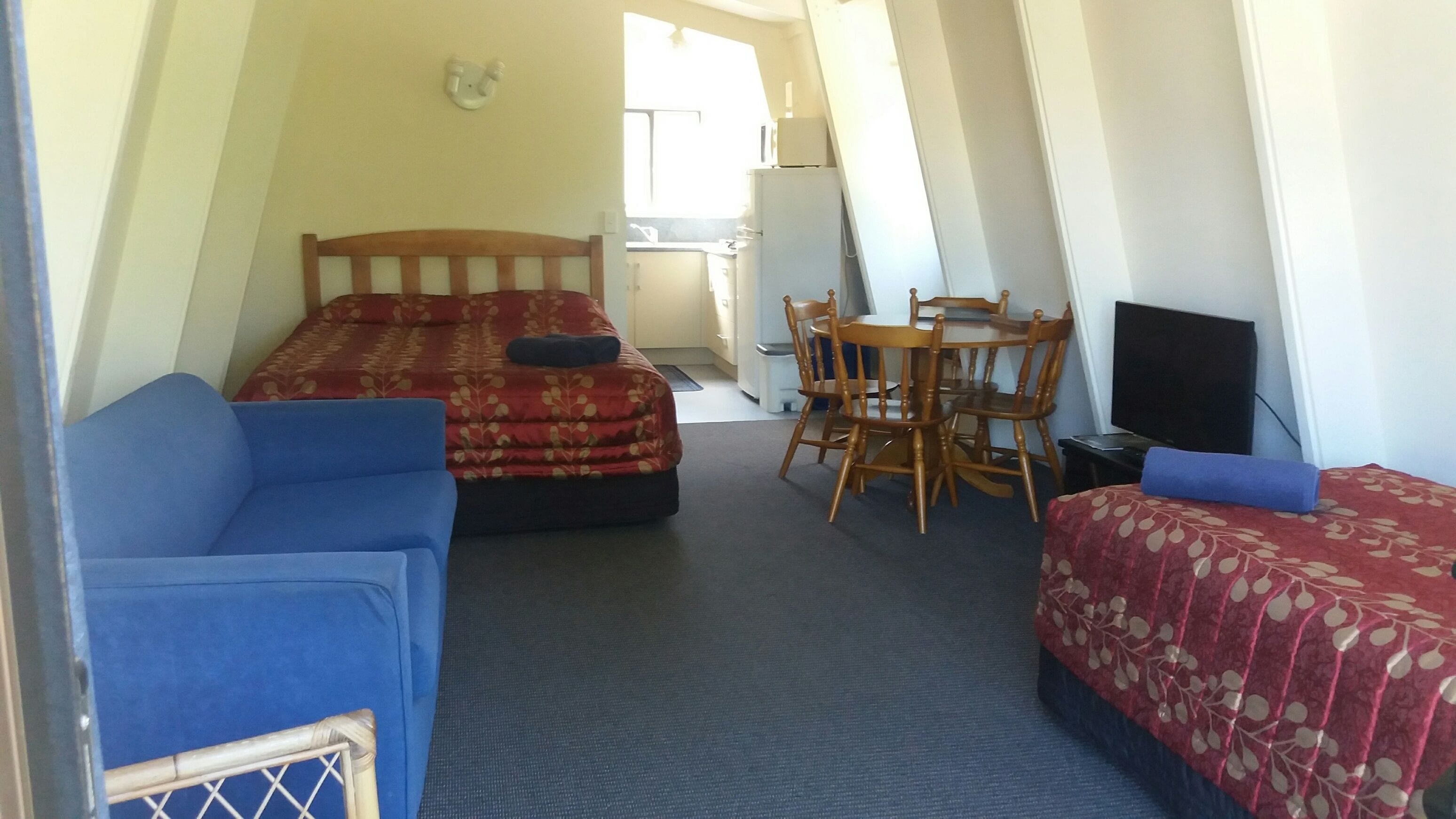 Une chambre de taille modeste, équipée de deux lits, d’une petite table et d’un téléviseur.