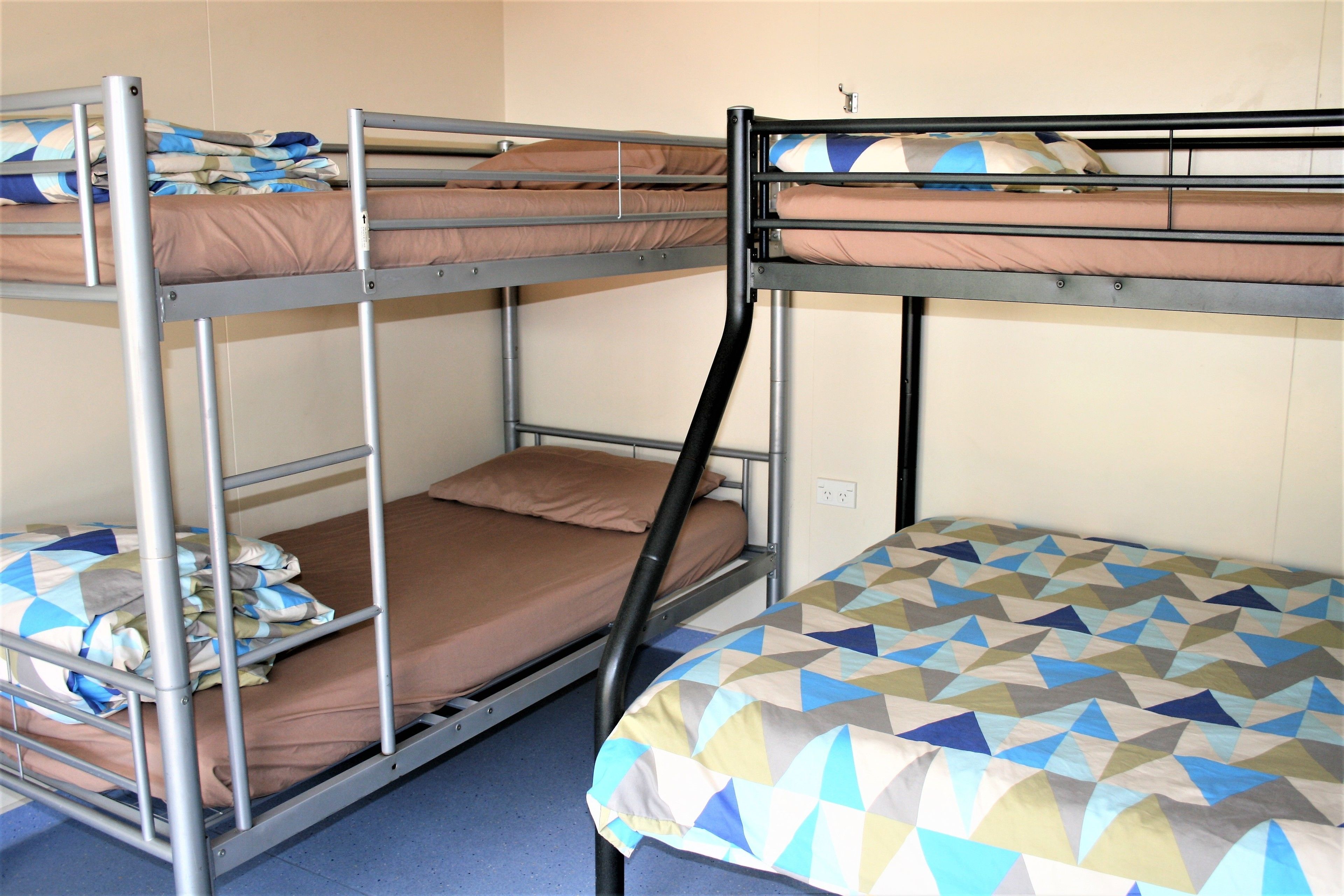 Dormitorio con literas, barandas metálicas y una colcha estampada.
