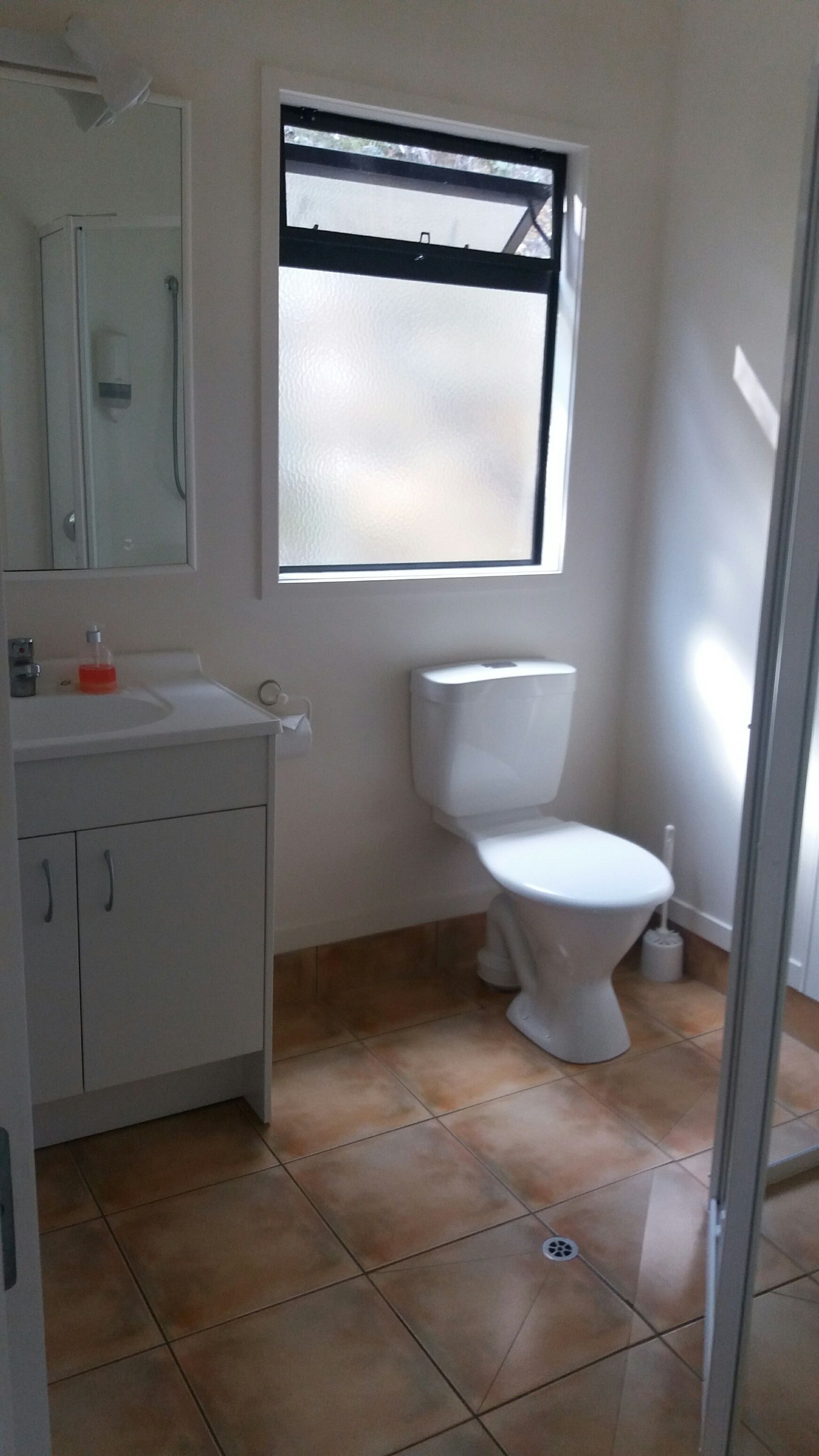 A bathroom with a toilet, a sink, and a mirror.
