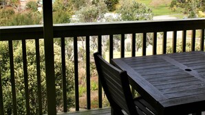 A wooden deck with a table and bench, overlooking a scenic landscape with trees and a body of water. - Whatuwhiwhi TOP 10 Holiday Park (Karkari Peninsula)