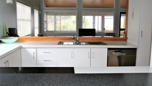 A modern kitchen with white cabinets, a stainless steel sink, and a black countertop. - Whatuwhiwhi TOP 10 Holiday Park (Karkari Peninsula)
