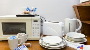 A kitchen area with a microwave, toaster, coffee maker, and various kitchen utensils and food items. - Innisfail City Motel (Innisfail)