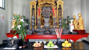 A shrine with golden statues, incense burners, and offerings on a black altar. - Innisfail City Motel (Innisfail)