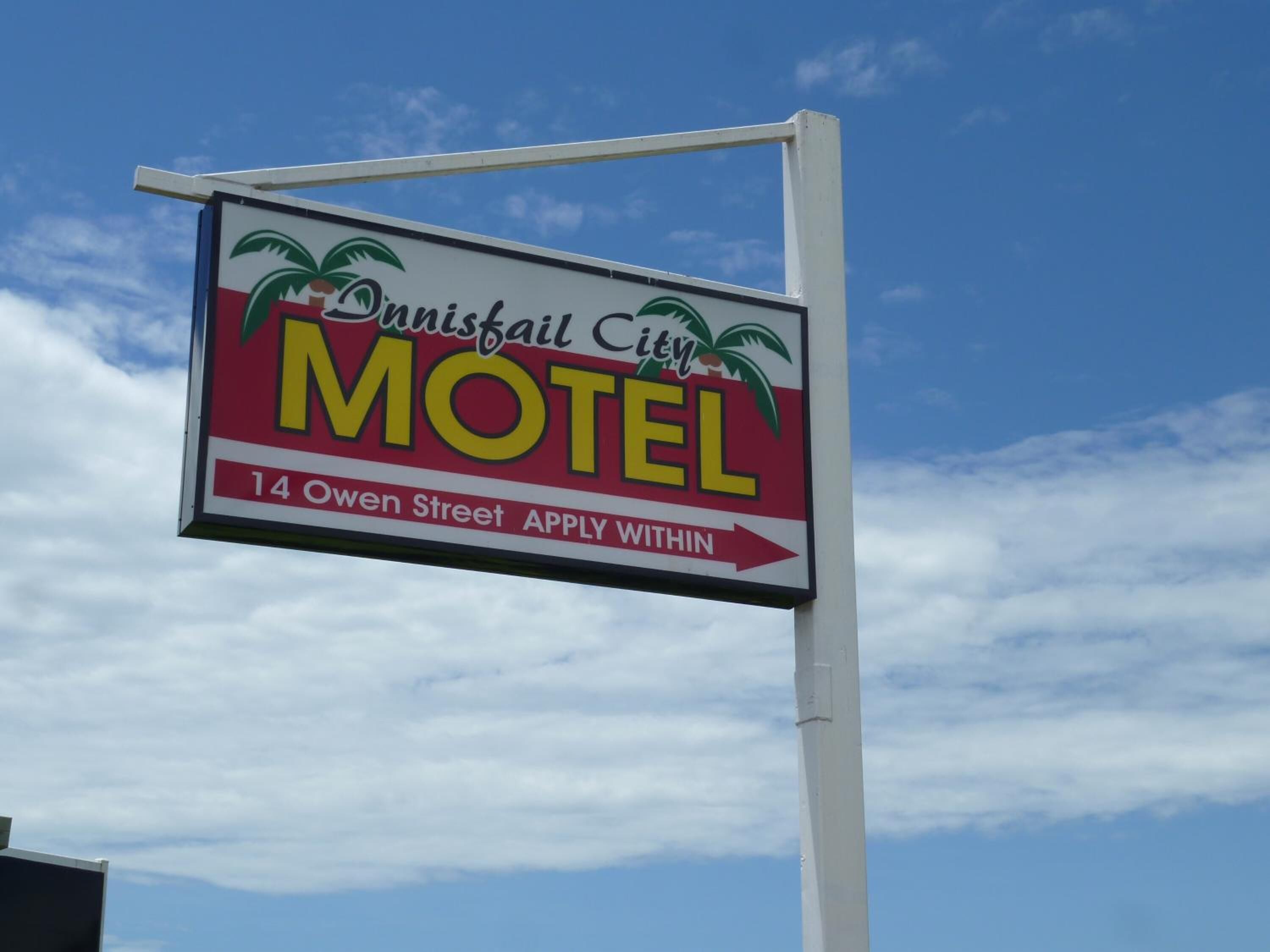 Une enseigne de motel ornée de motifs de palmiers et portant l’inscription : « Danisfail City MOTEL, 14, rue Owen. Les candidatures sont reçues sur place. »