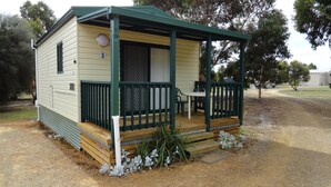 A small, single-story cabin with a porch and a fenced deck. - Kangaroo Island Cabins (Kingscote)