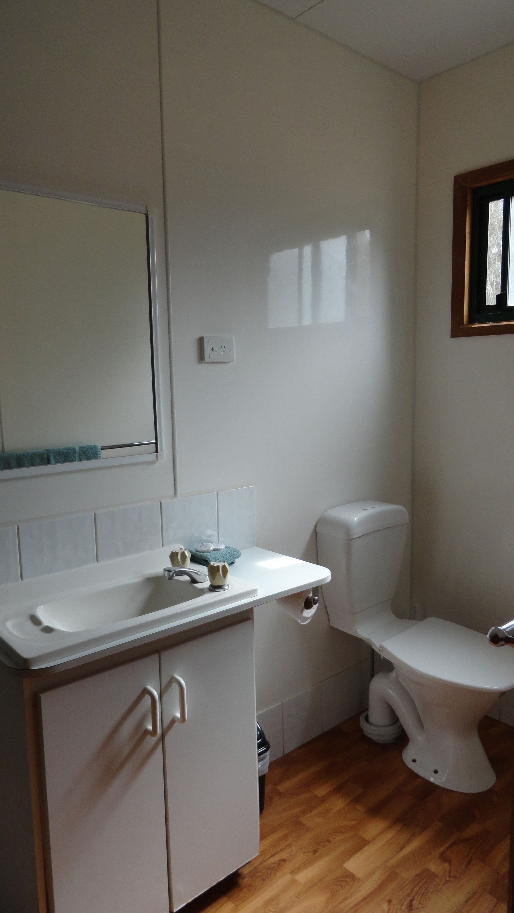 A bathroom with a white sink, toilet, and mirror.