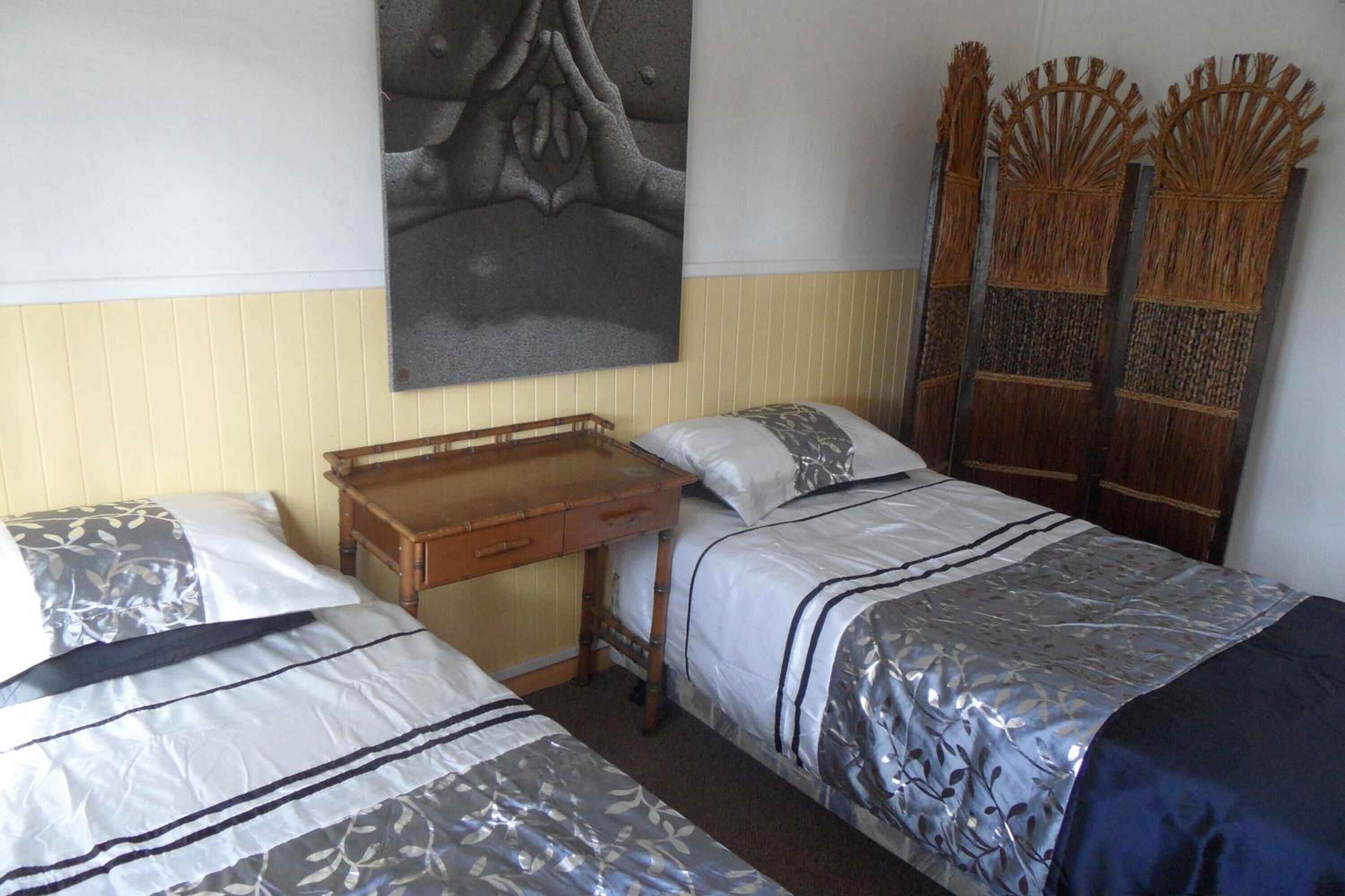 A room with two single beds, a wooden desk, and a wall-mounted artwork.