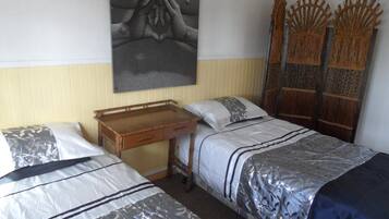 A room with two single beds, a wooden desk, and a wall-mounted artwork.