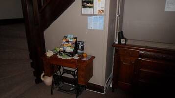 Une pièce comprenant un bureau en bois, une machine à coudre et un tableau d’affichage où sont accrochés des papiers et un calendrier.