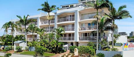 A multi-story hotel with balconies, palm trees, and a sign indicating availability.