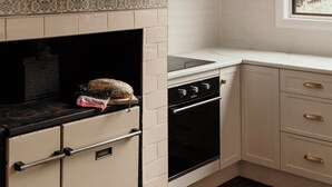 Una cocina con armarios blancos, estufa negra y una lámpara colgante.