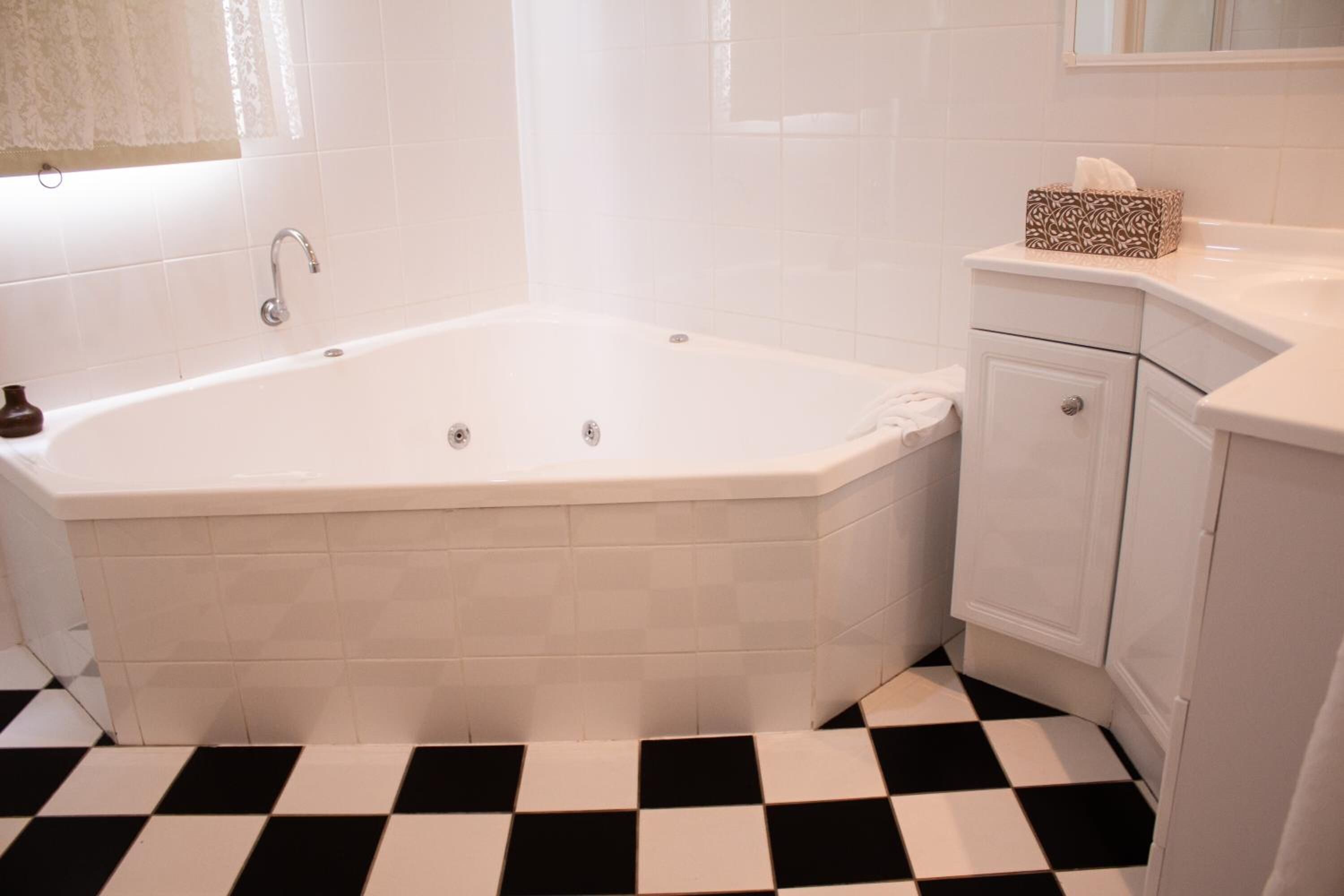 A bathroom with a white bathtub, a white sink, and a checkered floor.