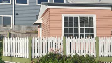 Un edificio residenziale con una recinzione in legno bianco, un'ampia finestra e un piccolo portico.