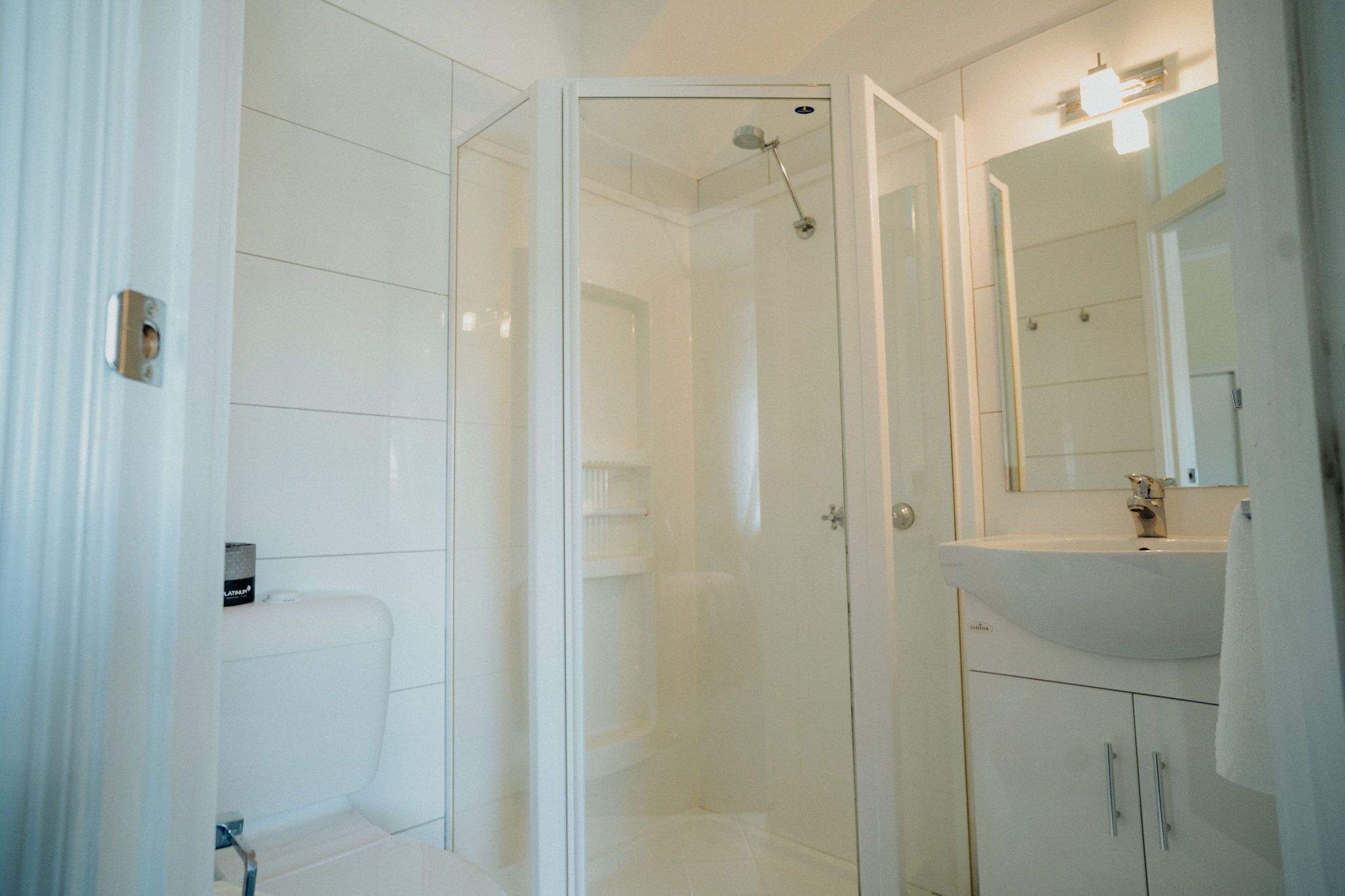 A modern bathroom with a glass-enclosed shower, a white sink, and a mirror.