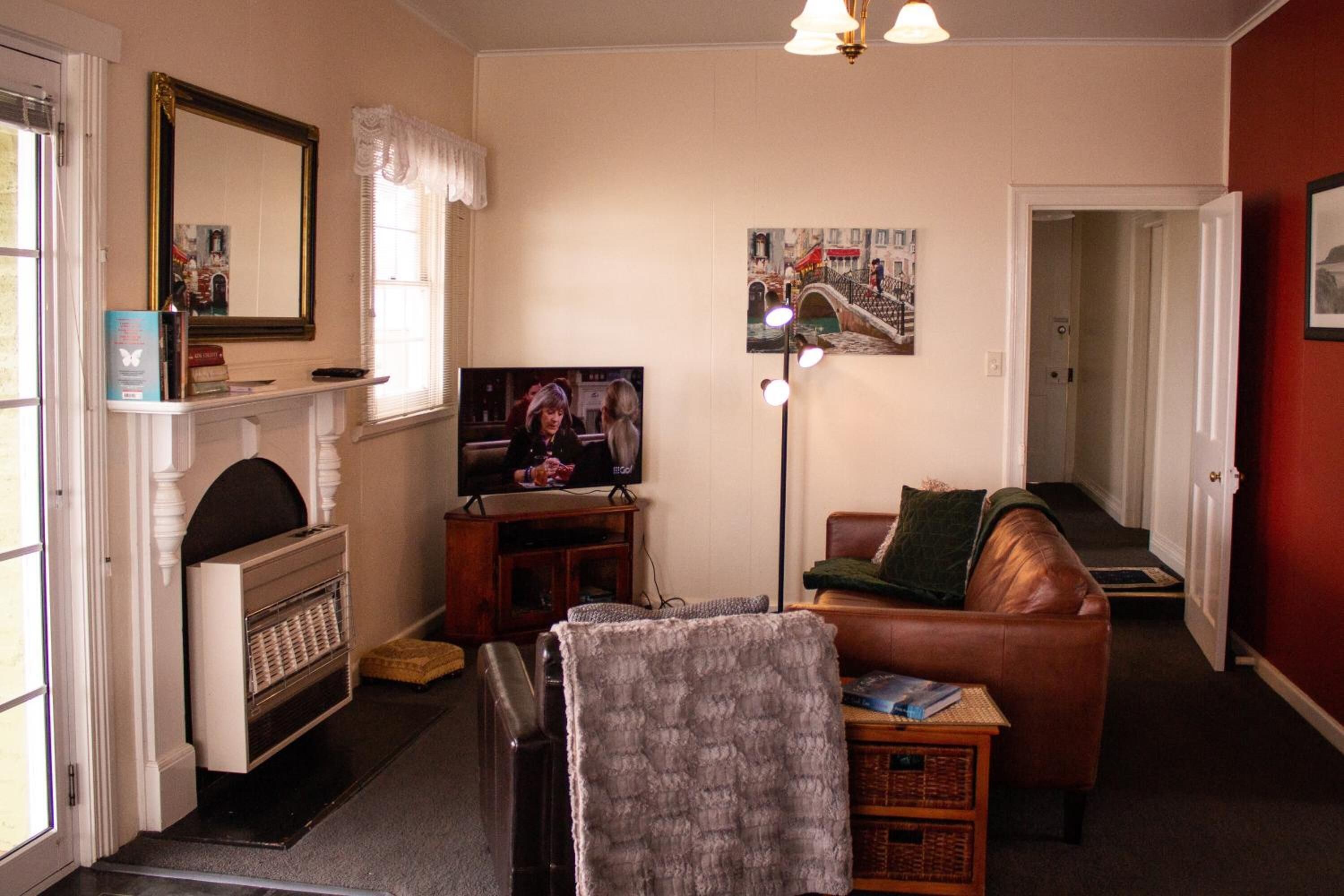 Een woonkamer met een open haard, een televisie, een bank en een deur naar een andere kamer.