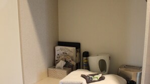 A small, enclosed bathroom with a shelf holding towels, a tissue box, and a small trash bin. - Dunolly Golden Triangle Motel (Dunolly)
